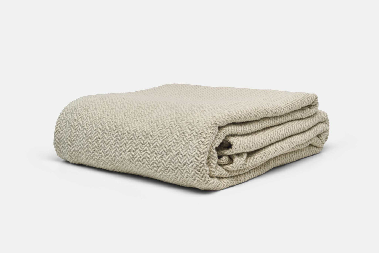 Herringbone weave cotton blanket folded in beige soft fabric for cozy layering