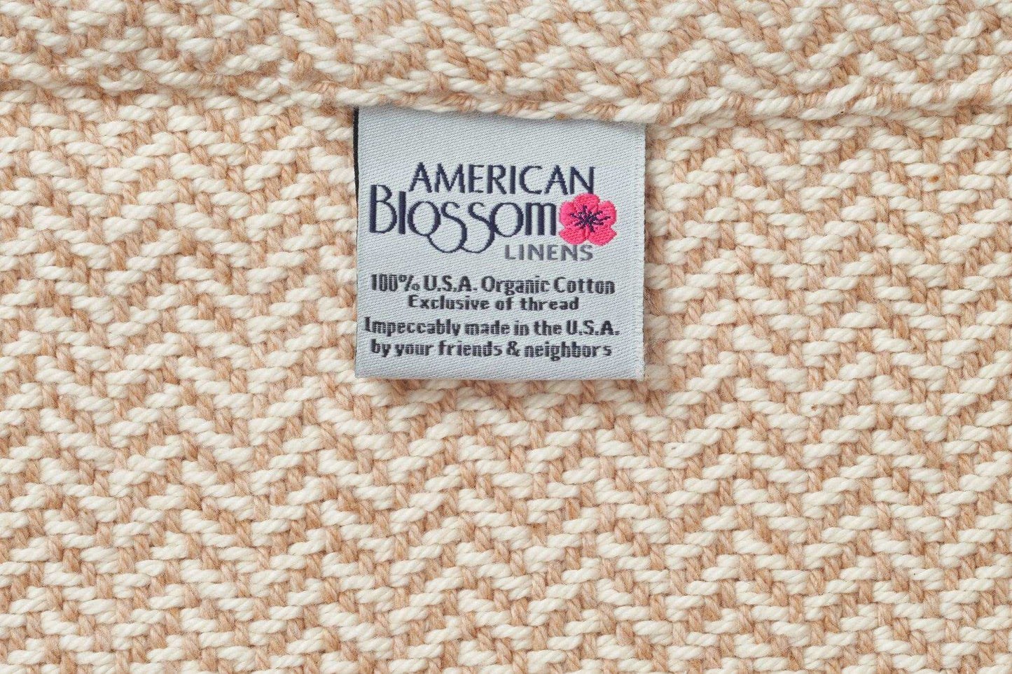 Close-up of beige herringbone weave cotton blanket with American Blossom Linens label