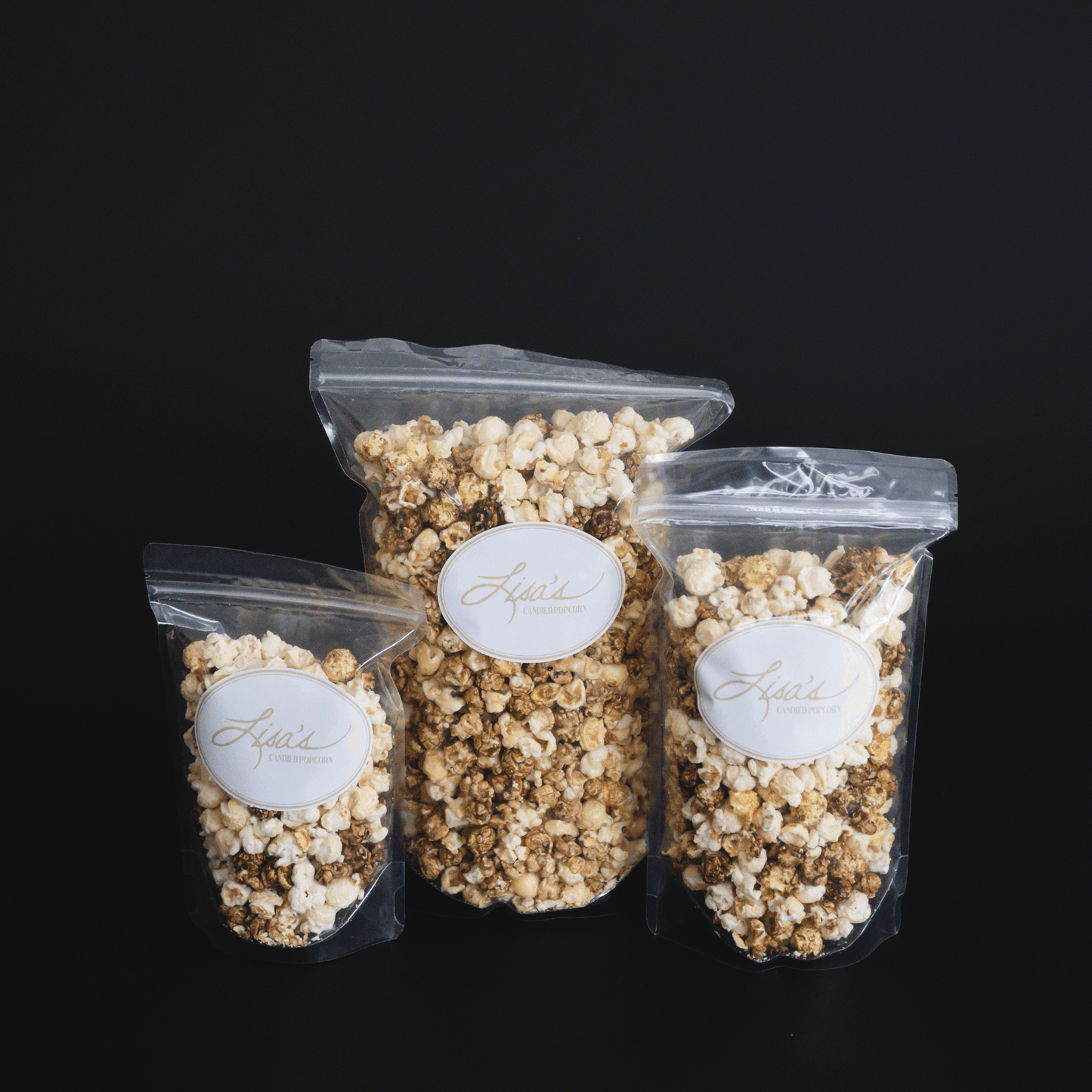 Three clear bags of candied cinnamon roll popcorn in snack, share, and celebrate sizes against a black background