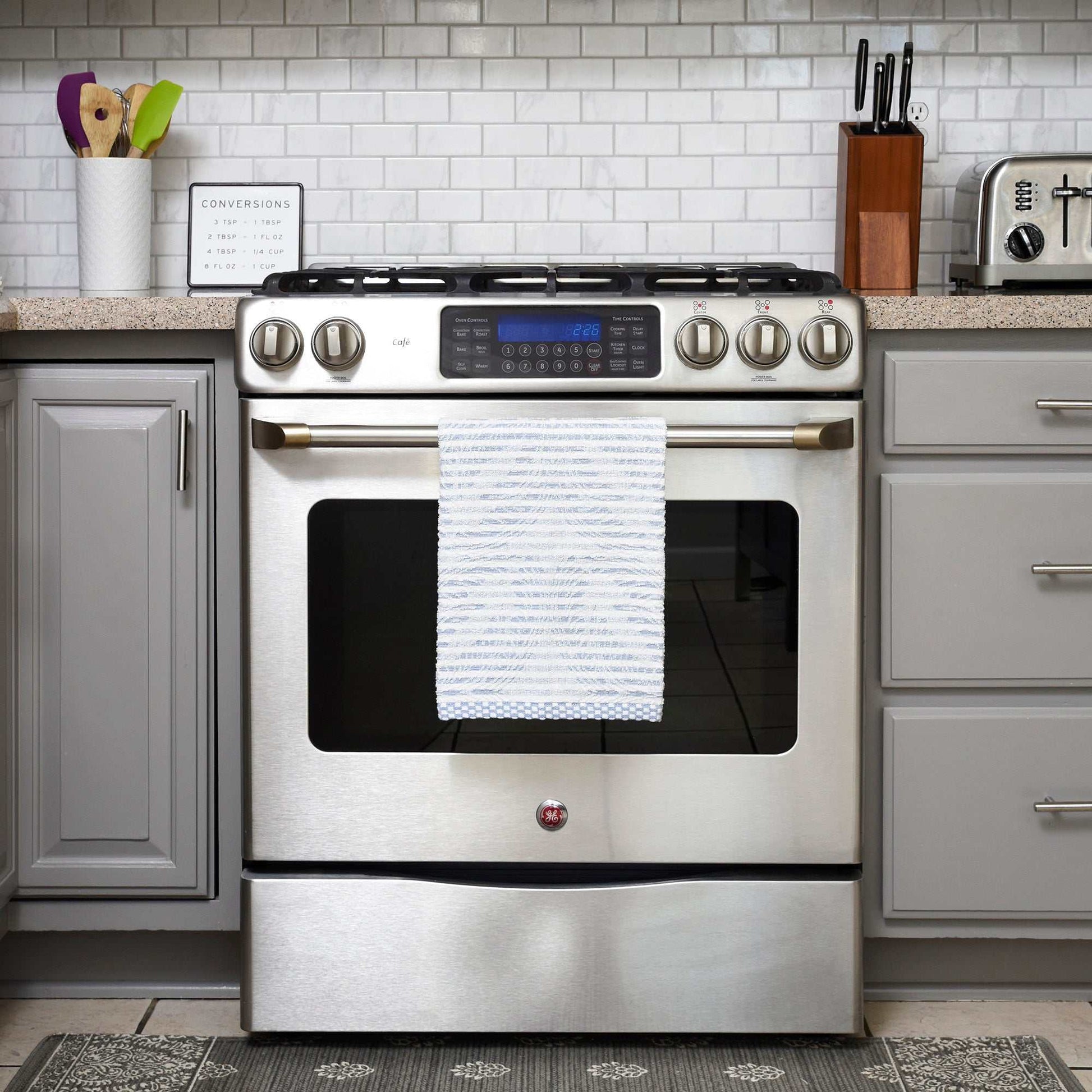 Organic cotton kitchen towel hanging on stainless steel oven handle in modern kitchen