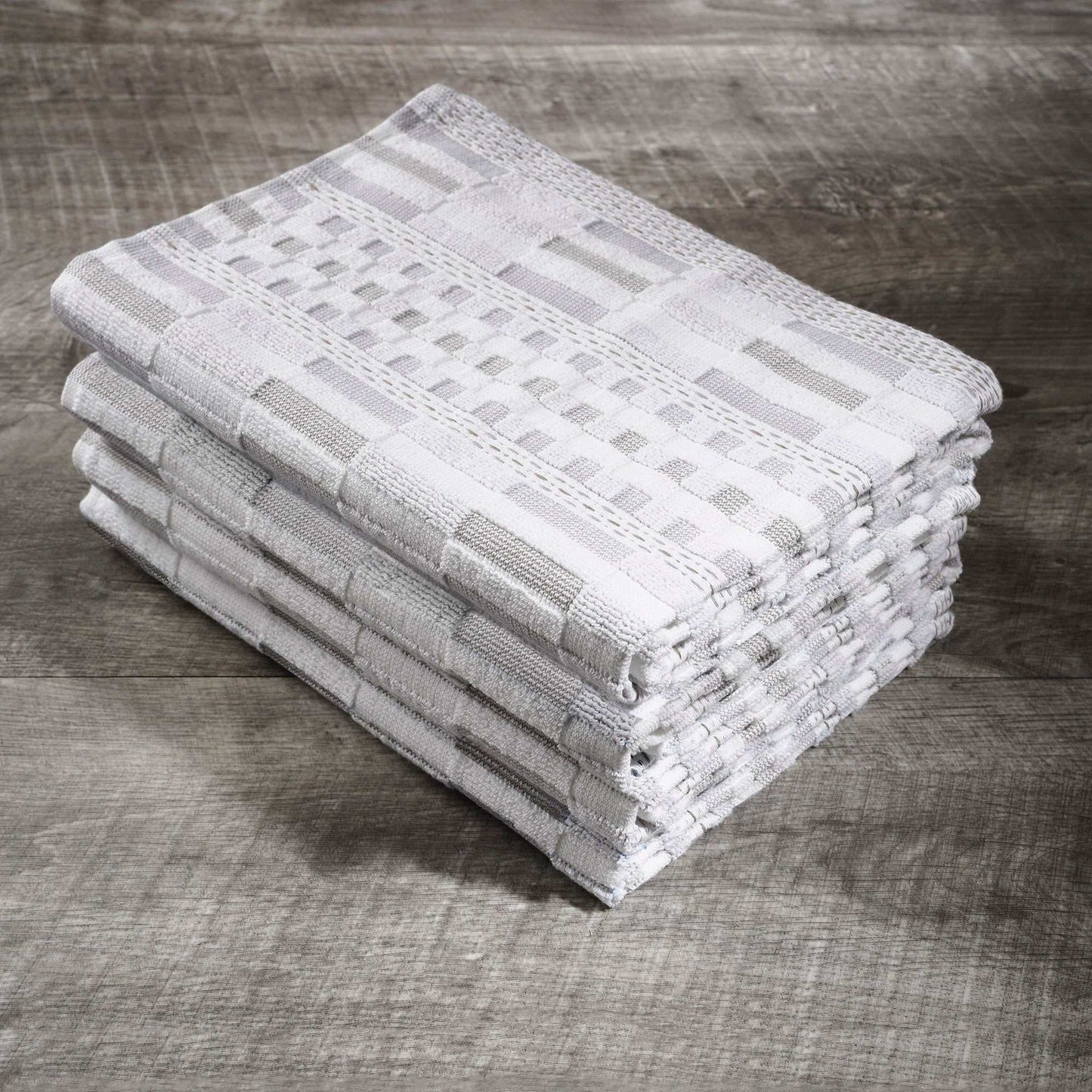 Stack of white organic cotton kitchen towels with textured pattern on wooden surface