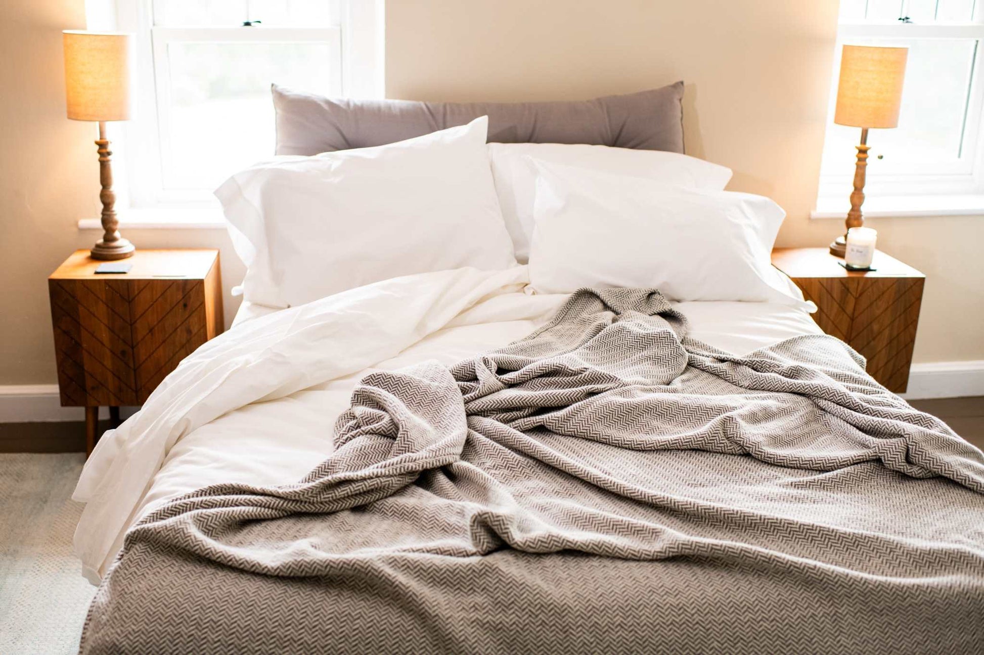 Herringbone weave cotton blanket draped over white bed in cozy bedroom setting