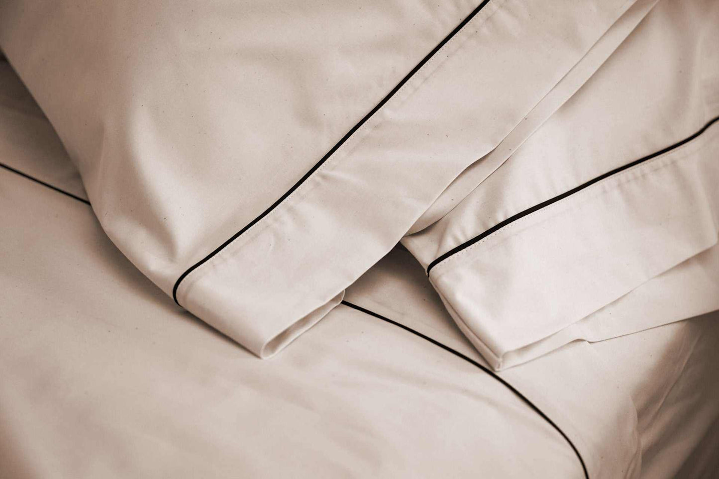 Close-up of cotton piping design bed sheet set with elegant black piping on natural-colored fabric