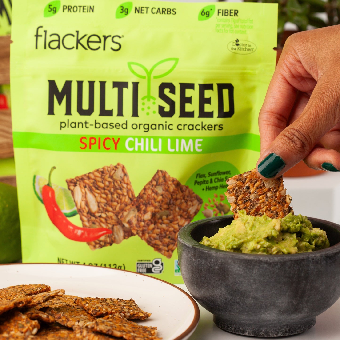 Spicy Chili Lime Multi Seed Crackers dipping into guacamole with bright green Flackers package in background