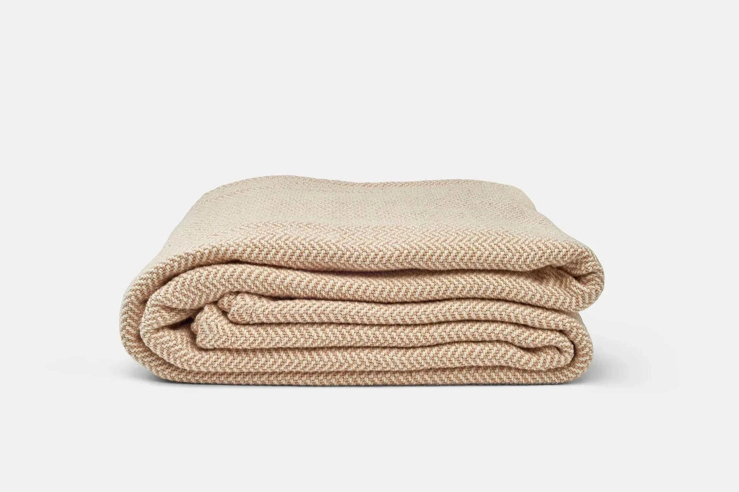 Folded beige herringbone weave cotton blanket for sofa or bed
