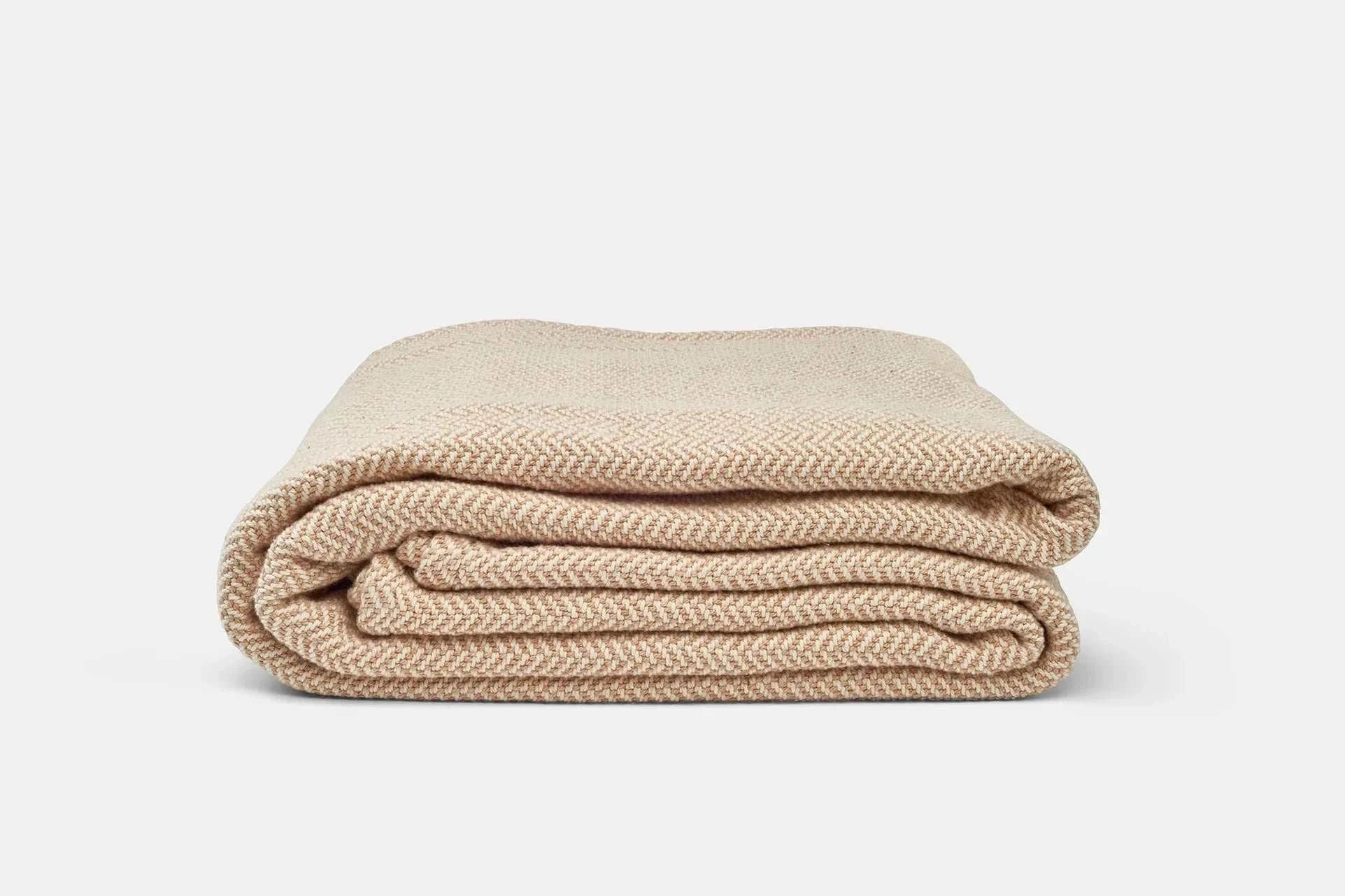 Folded beige herringbone weave cotton blanket for sofa or bed