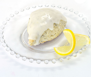 Farmhouse Mornings lemon poppyseed scone with glaze on clear plate and lemon wedges