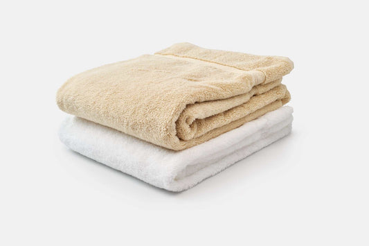 Stack of luxury USA cotton bath towels in beige and white with high absorbency and softness