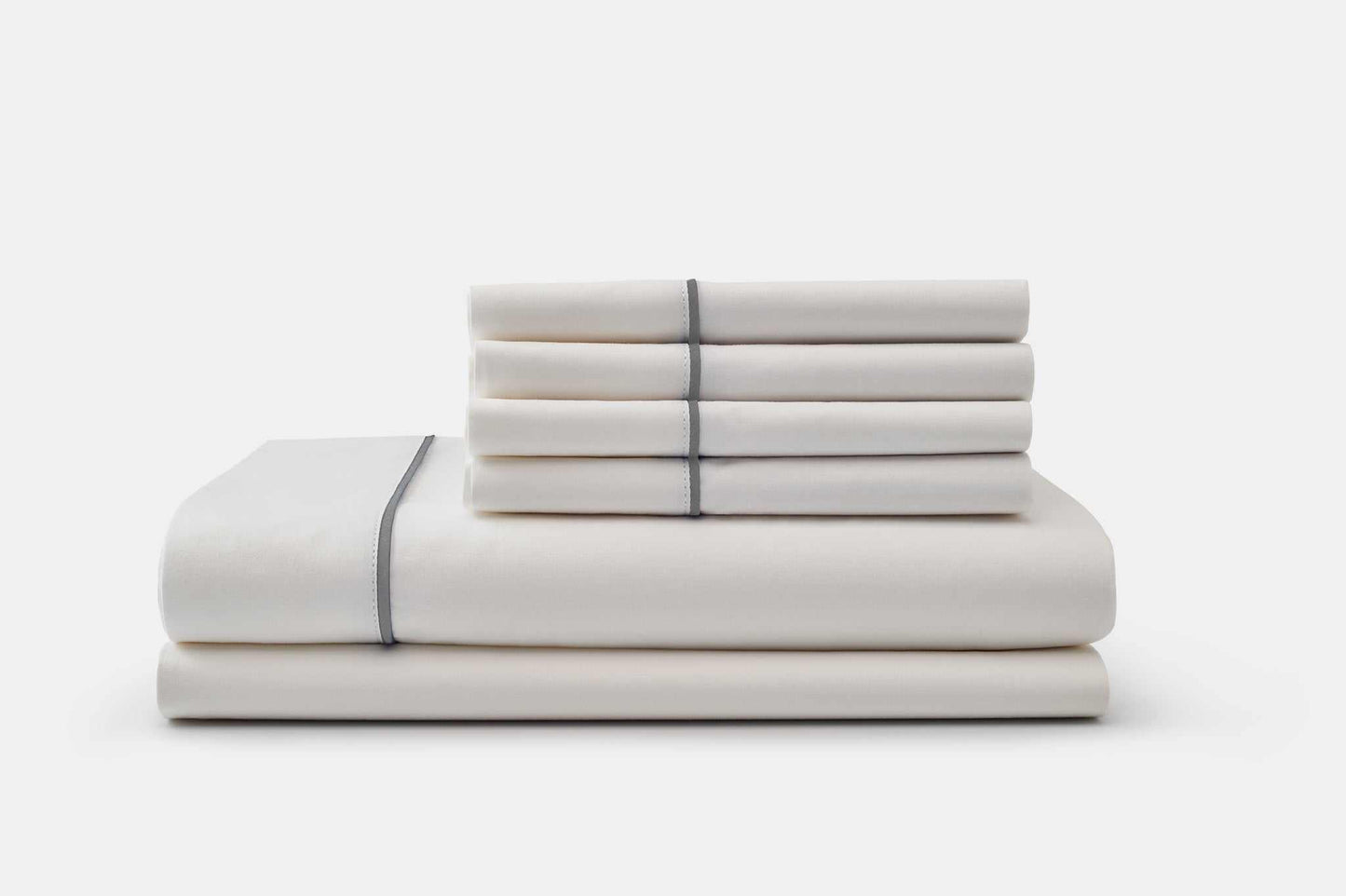 Stacked white cotton bed sheets with grey piping design set