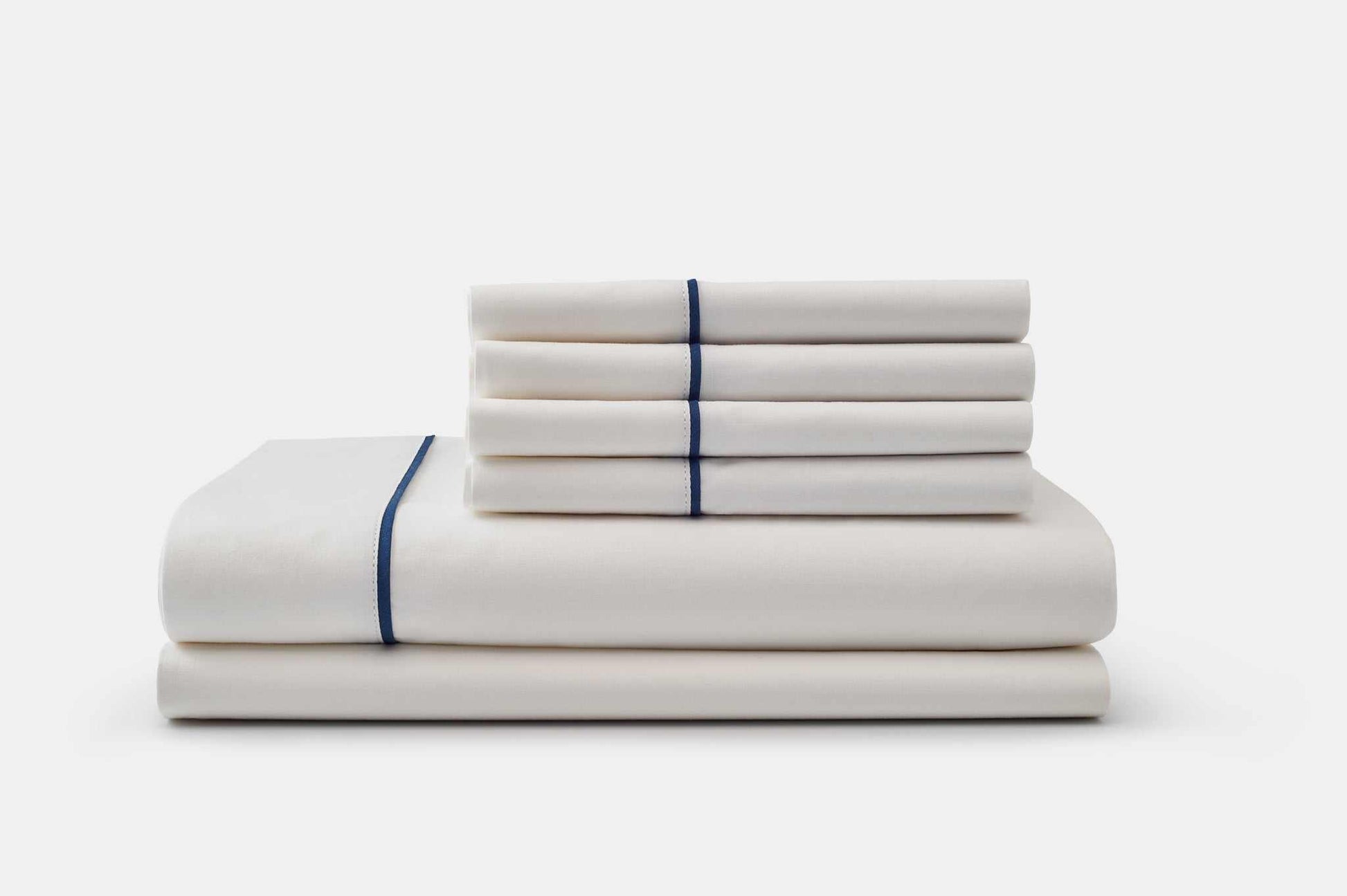 White cotton bed sheet set with blue piping design stacked neatly