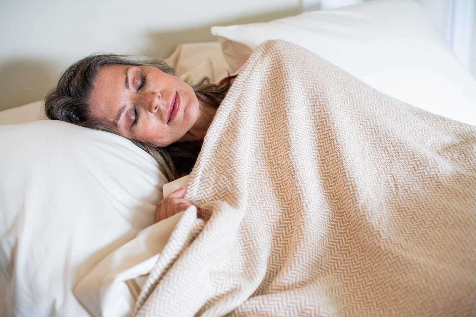Woman sleeping comfortably under a soft herringbone weave cotton blanket in bed