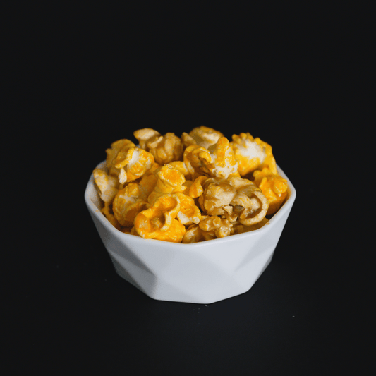 Bowl of caramel and cheddar popcorn mix against black background