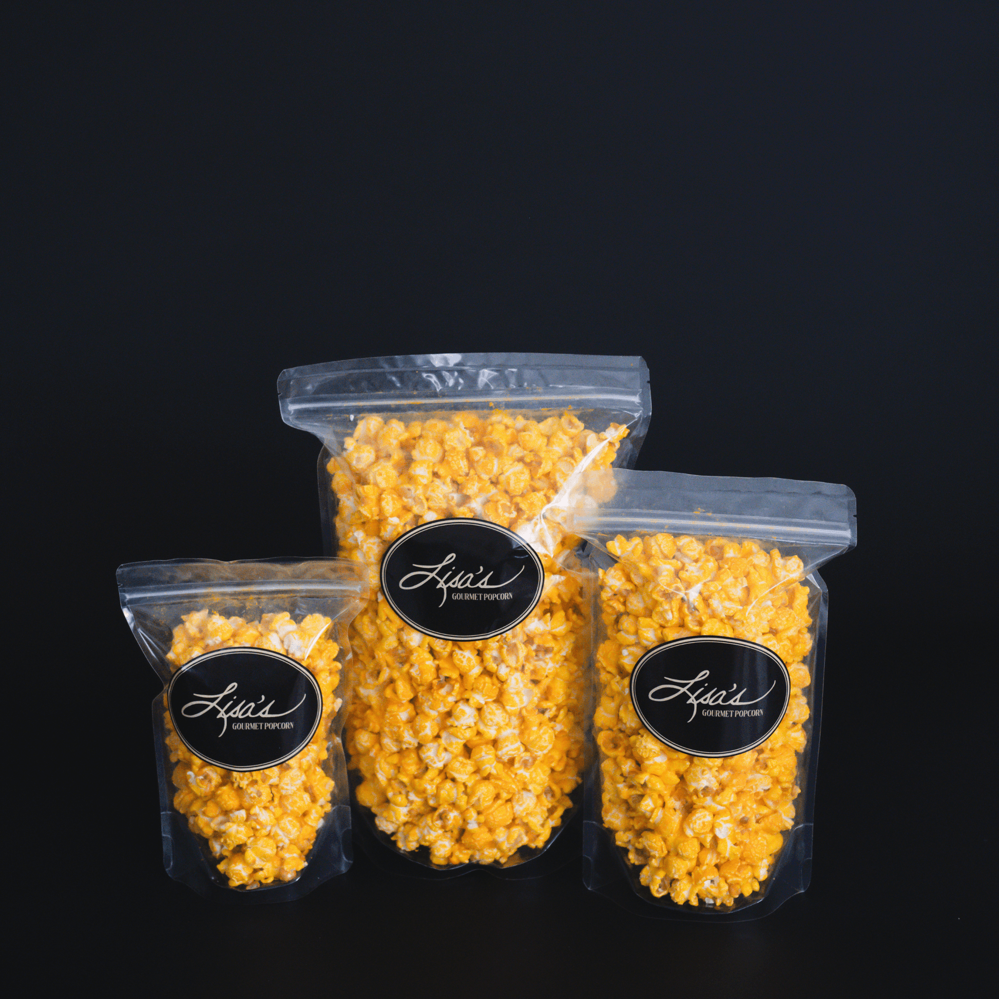 Three clear resealable bags of cheddar cheese popcorn in snack, share, and celebrate sizes against a black background