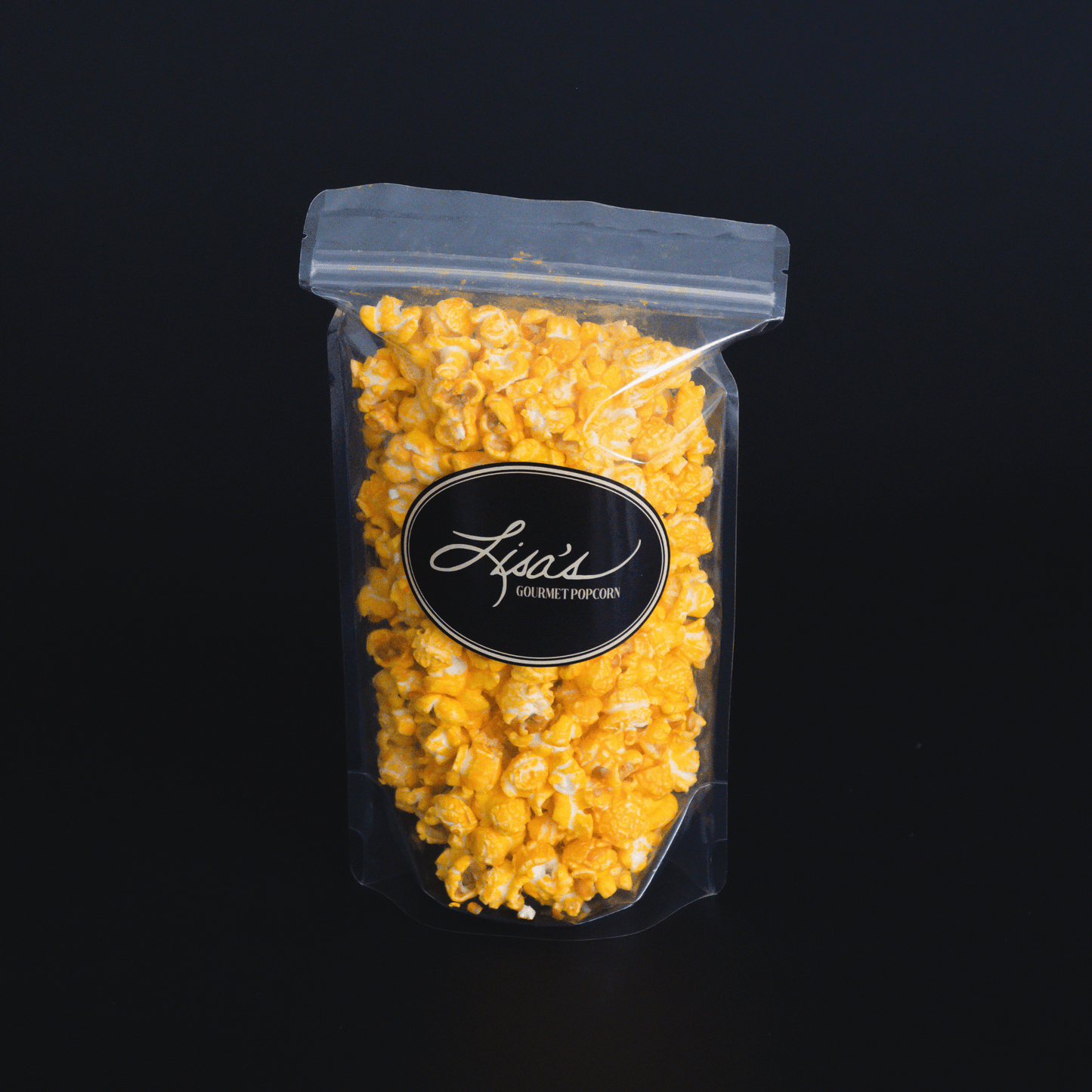 Cheddar Cheese Popcorn in resealable clear bag with black label on black background