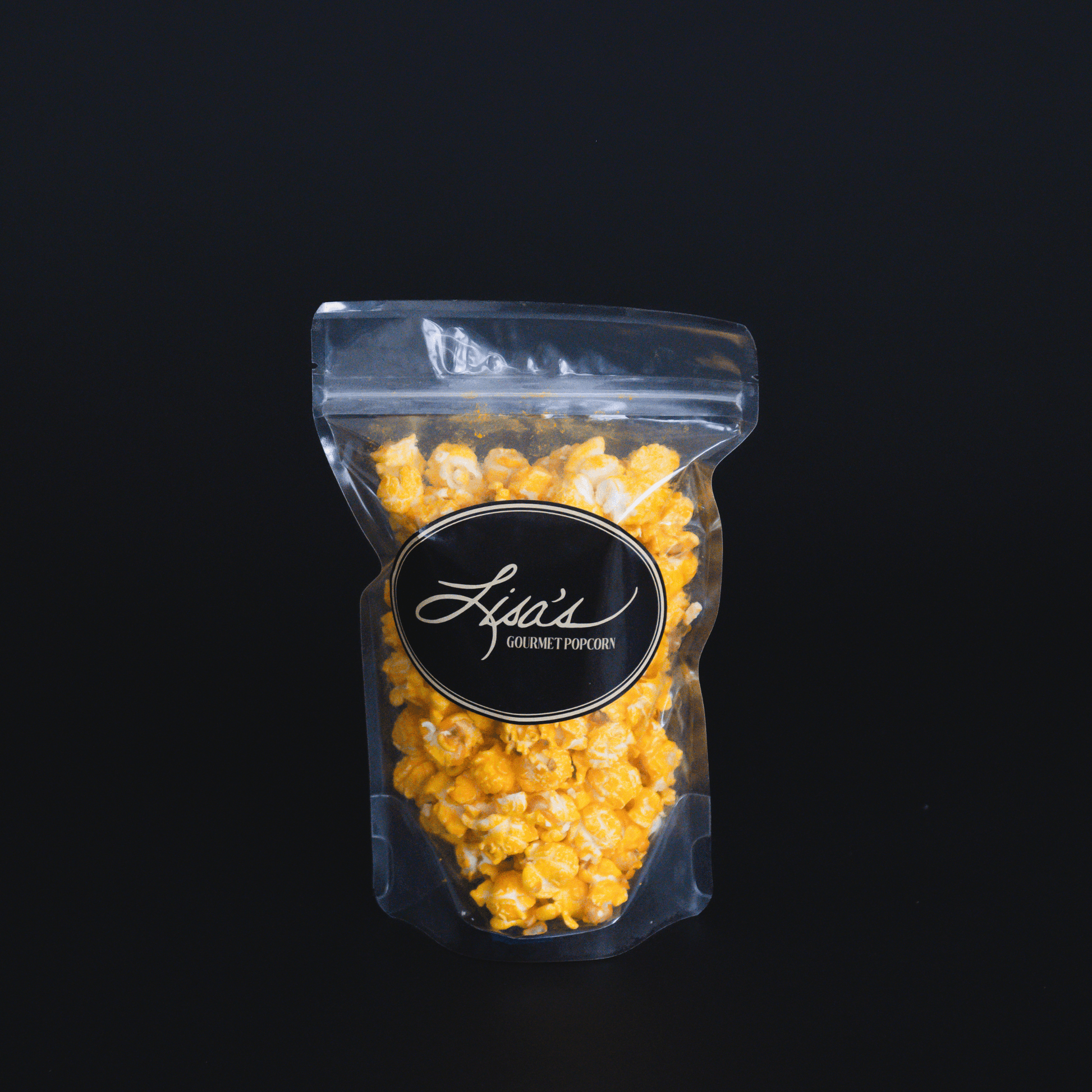 Cheddar cheese popcorn in a clear resealable bag with black label against black background