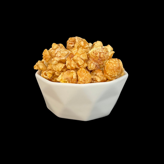 white bowl of churro popcorn with caramel cinnamon sugar coating on black background