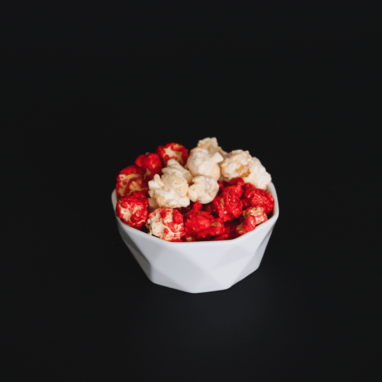 bowl of sweet and spicy candied cinnamon popcorn on black background