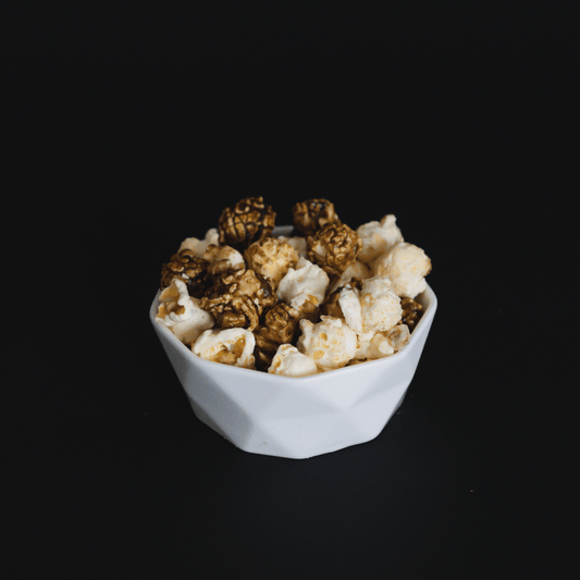 Bowl of cinnamon roll popcorn with candied cinnamon and vanilla flavors against black background