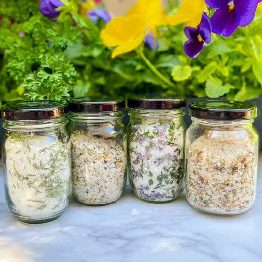 Dark Truffle Mushroom seasoning salt in glass jars with herbs and flowers background