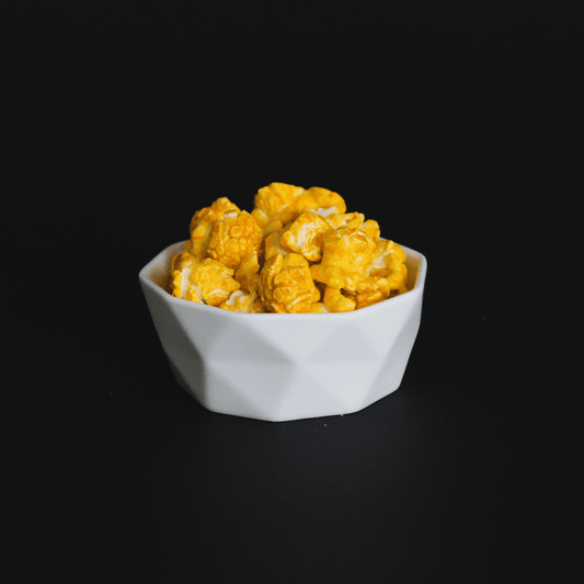 Bowl of spicy Jalapeño Cheddar Popcorn with cheddar cheese coating on black background