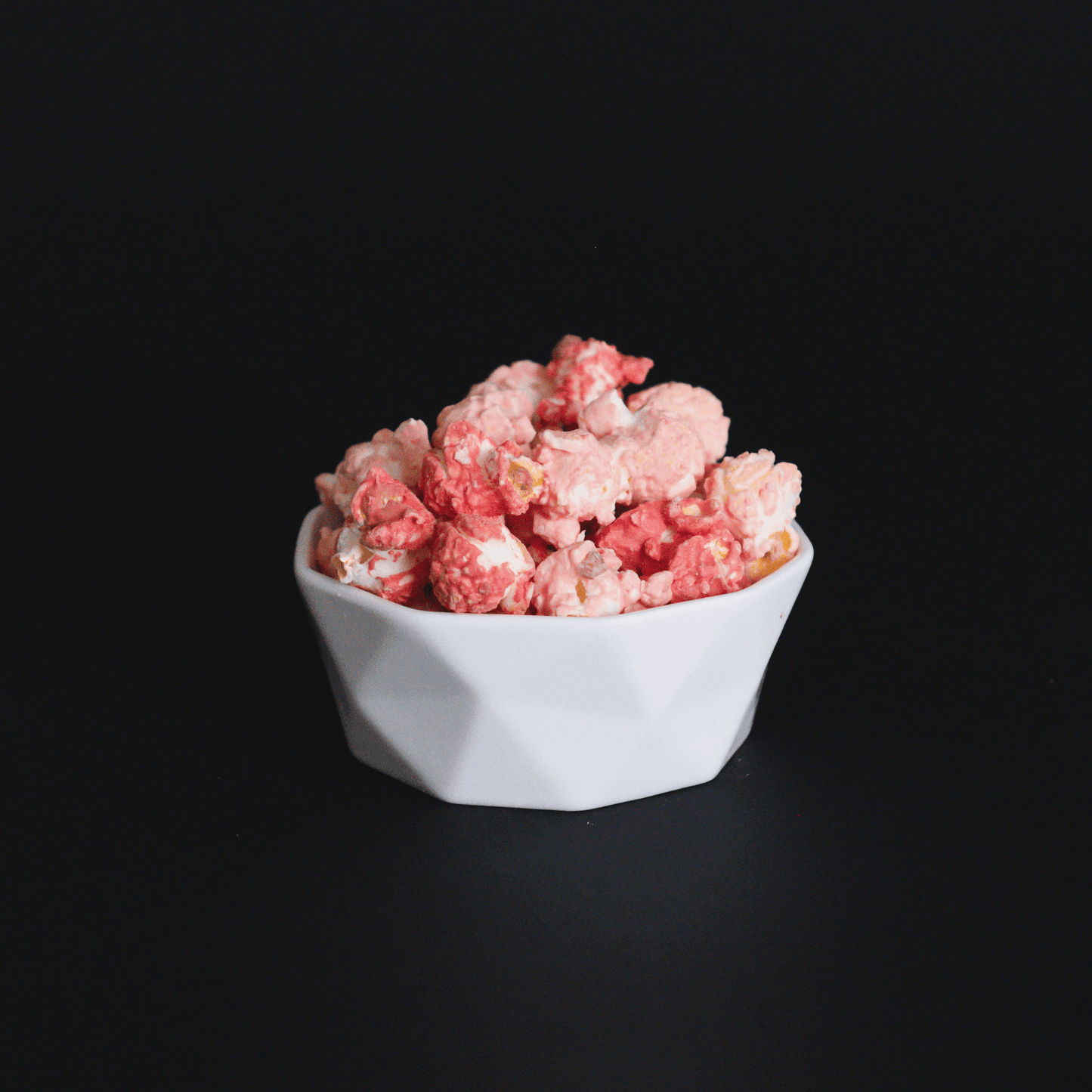 Bowl of Raspberry Dream Popcorn with white chocolate and raspberry flavor on black background