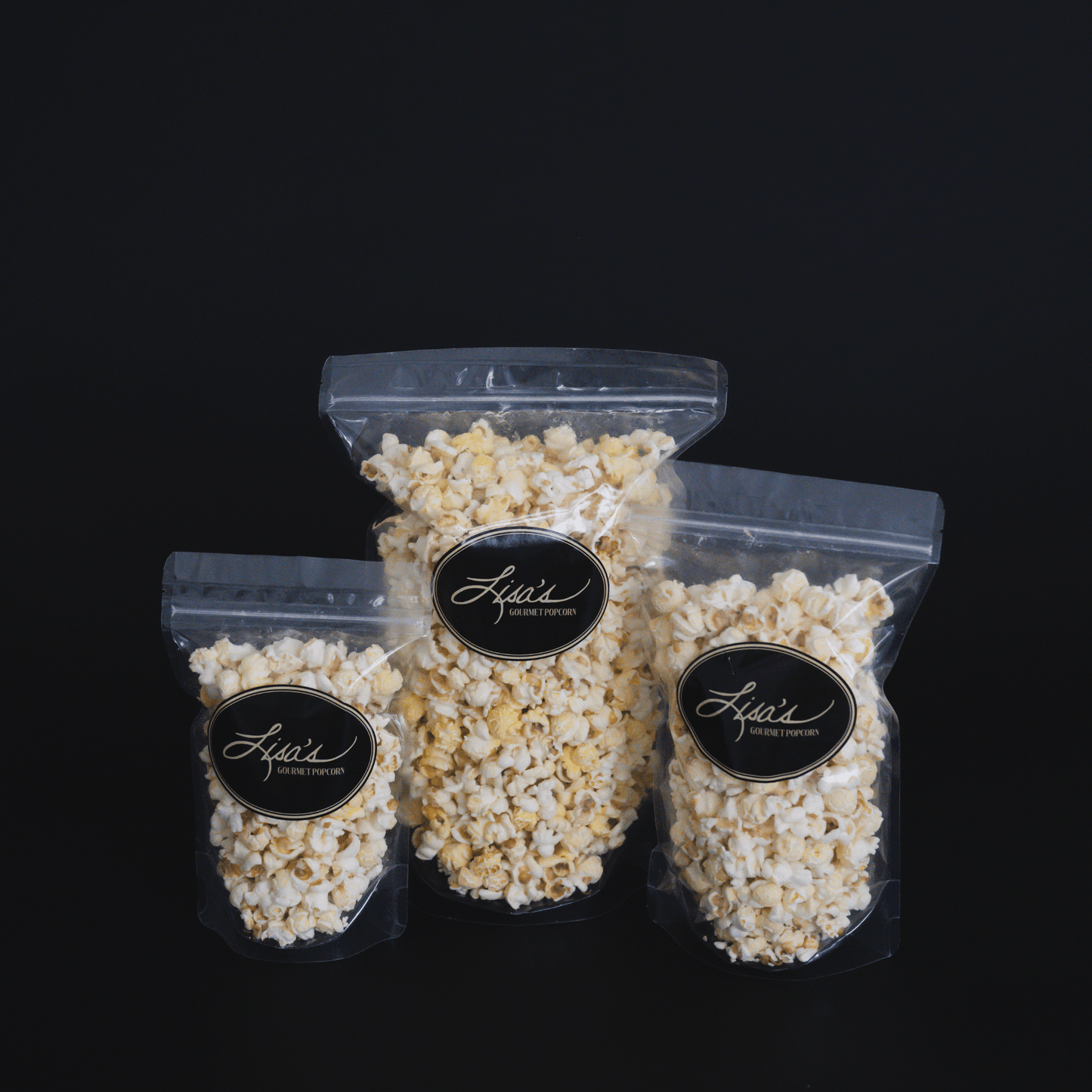 Three resealable bags of Lisa's white cheddar popcorn in snack, share, and celebrate sizes against a black background
