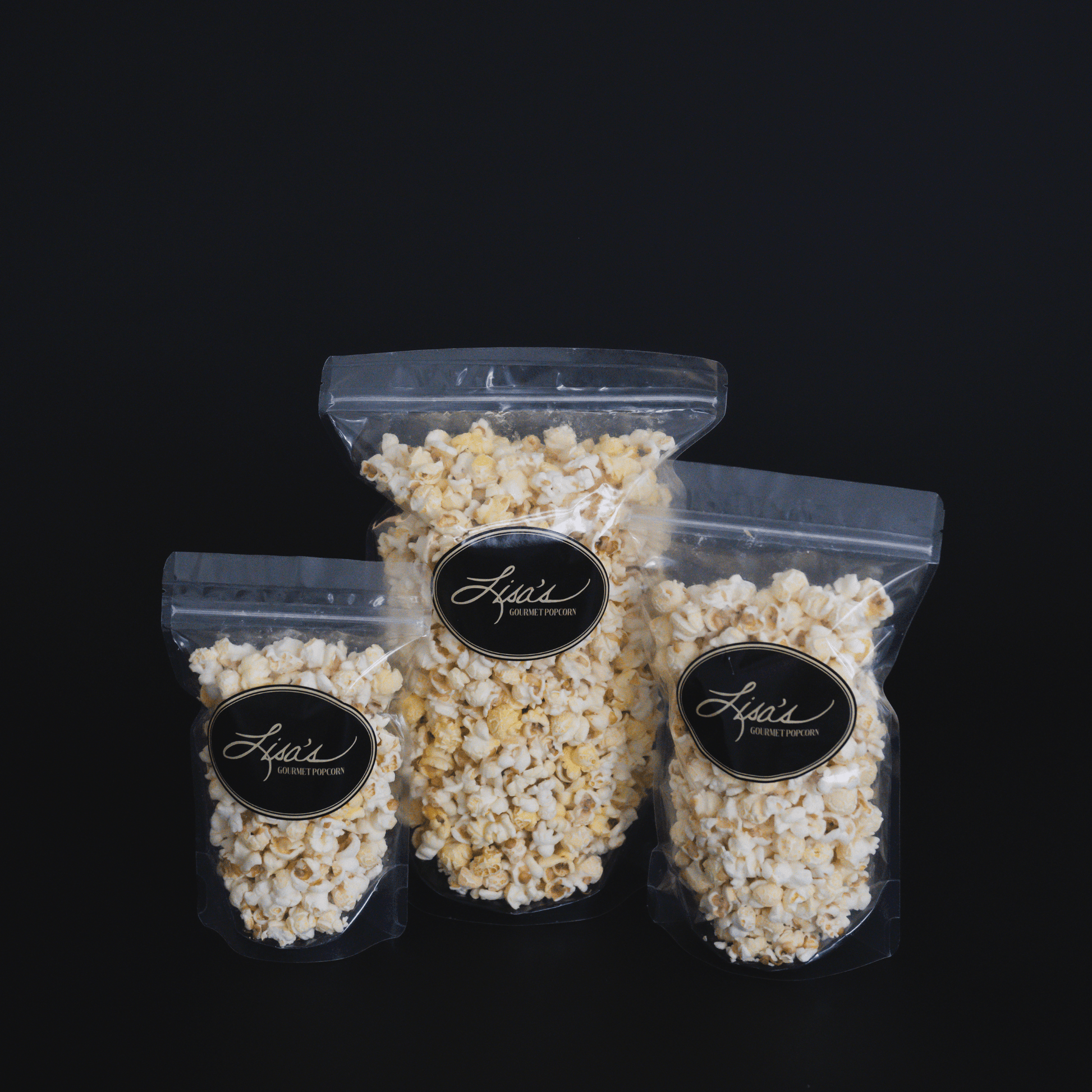 Three resealable bags of Lisa's white cheddar popcorn in snack, share, and celebrate sizes against a black background