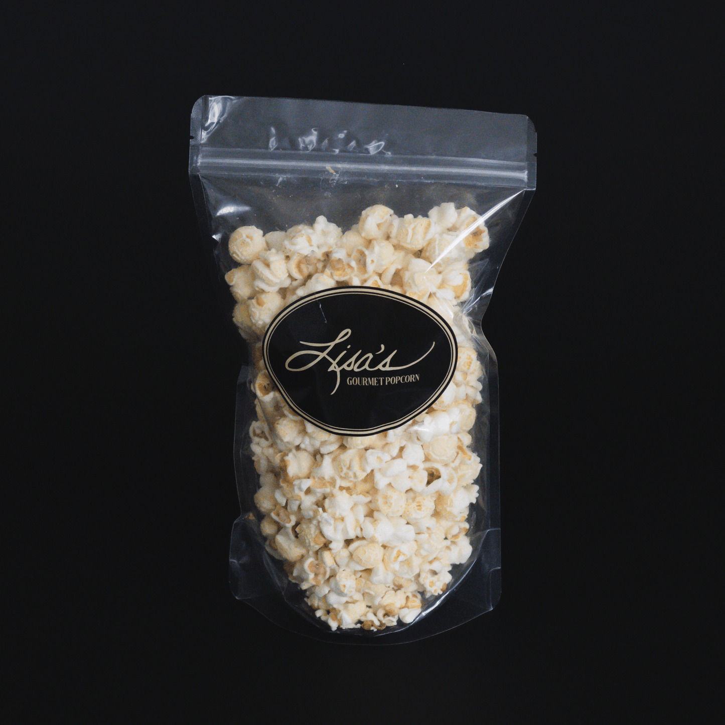 Clear resealable bag of white cheddar popcorn with black and gold label on black background