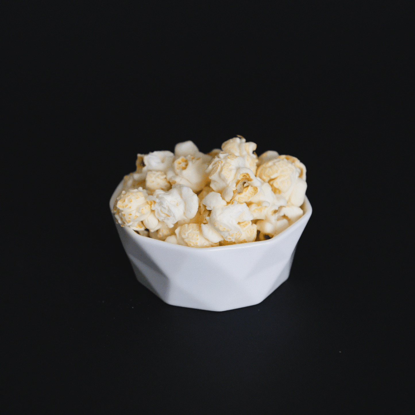 bowl of white cheddar popcorn snack on black background