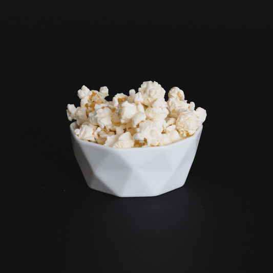 white chocolate popcorn in a white bowl on black background gourmet creamy snack